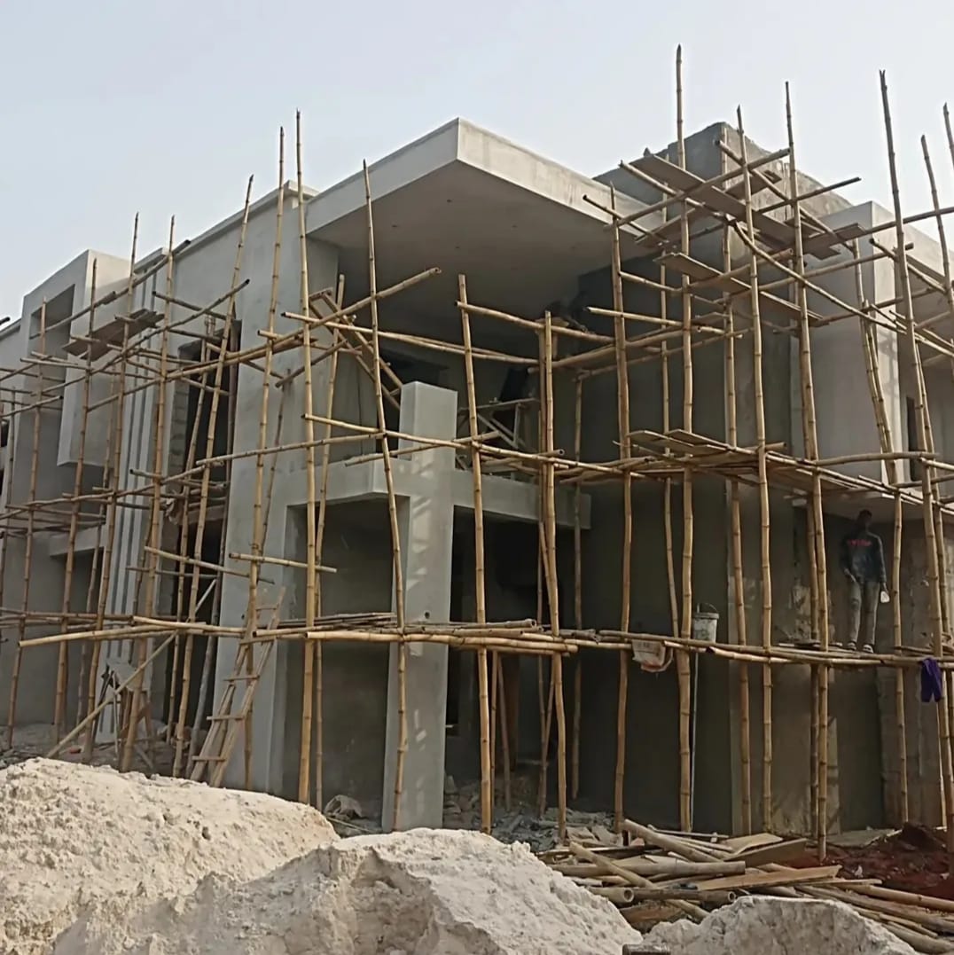 Bamboo scaffolding wraps a rendered facade mid-finish.