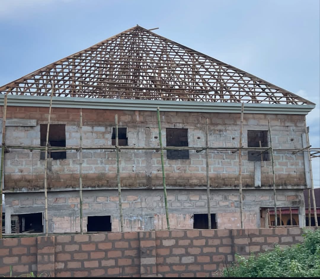 Timber roof trusses going up over a block shell